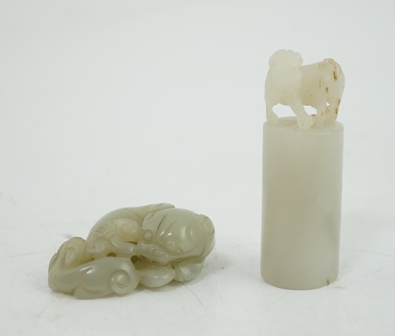 A Chinese white jade lion-dog seal and a Chinese pale celadon jade group of a lion dog and cub, 19th century